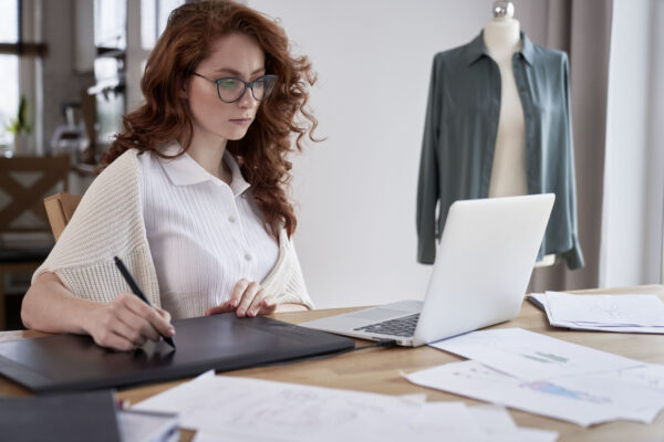 Young adult woman using laptop and designing a dress